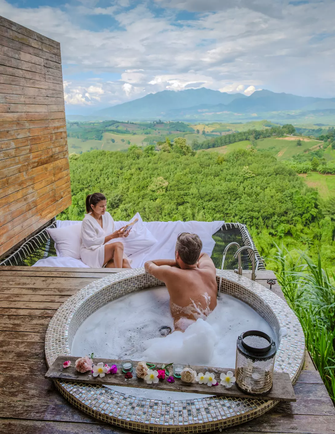 A couple relaxes in a hot tub and a hammock overlooking the hills of northern Thailand.