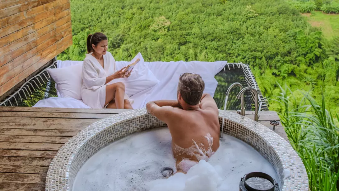 A couple relaxes in a hot tub and a hammock overlooking the hills of northern Thailand.