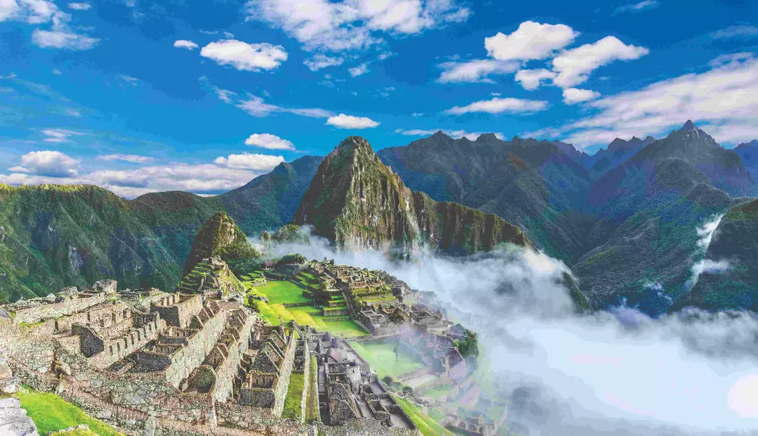 ruins of machu picchu draped in mist with backdrop of mountains