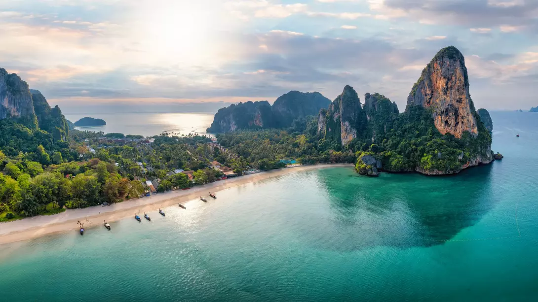 Panoramic aerial view of the beautiful Railay beach, lush rain forest and emerald sea during morning sunrise without people
