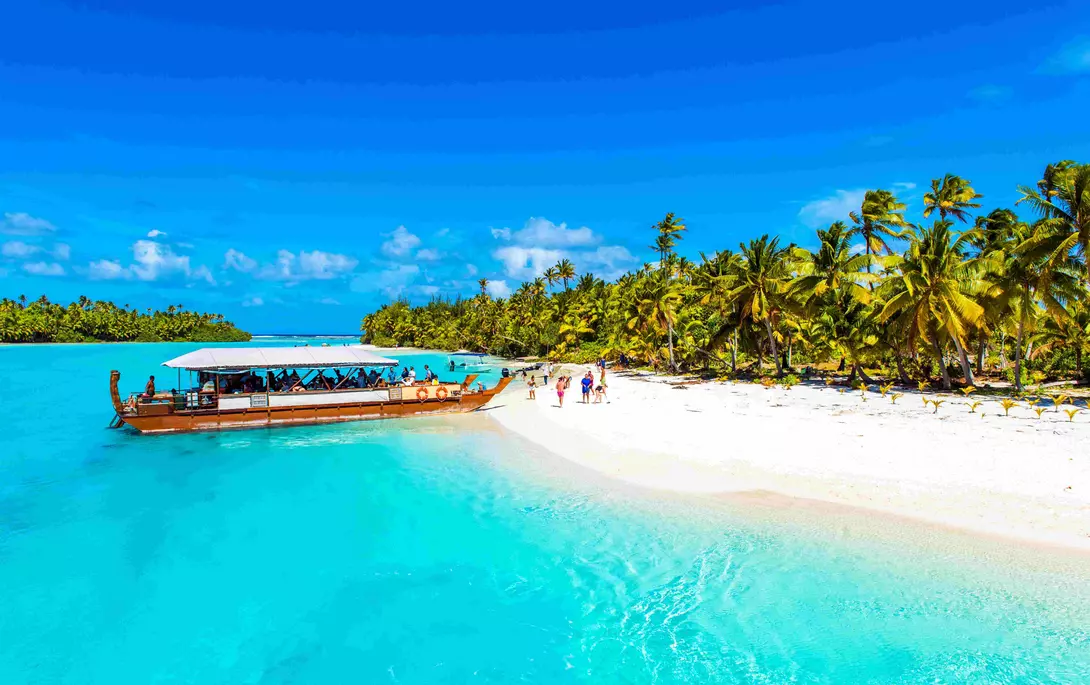 a boat moored next to a white sand beach on a tropical island