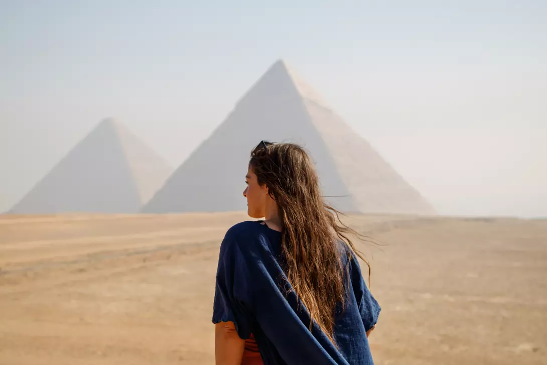 Long-haired woman standing on her back looking at the pyramids of Giza, Egypt