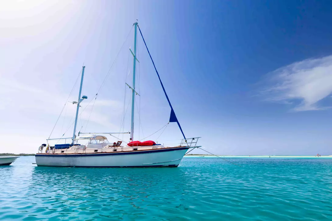 Sailboat anchored at a tropical turquoise island.