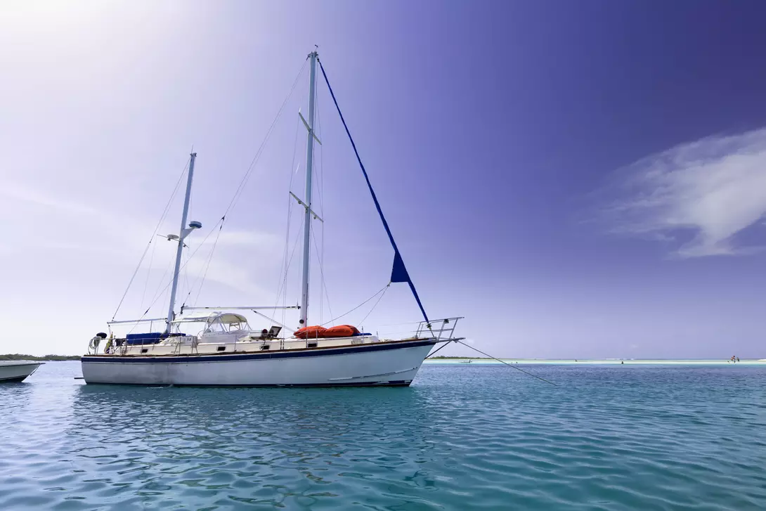 Sailboat anchored at a tropical turquoise island.