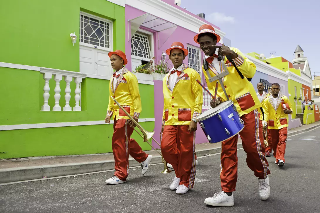 Minstrels dressed up carrying their musical instruments, trumpets and drum
