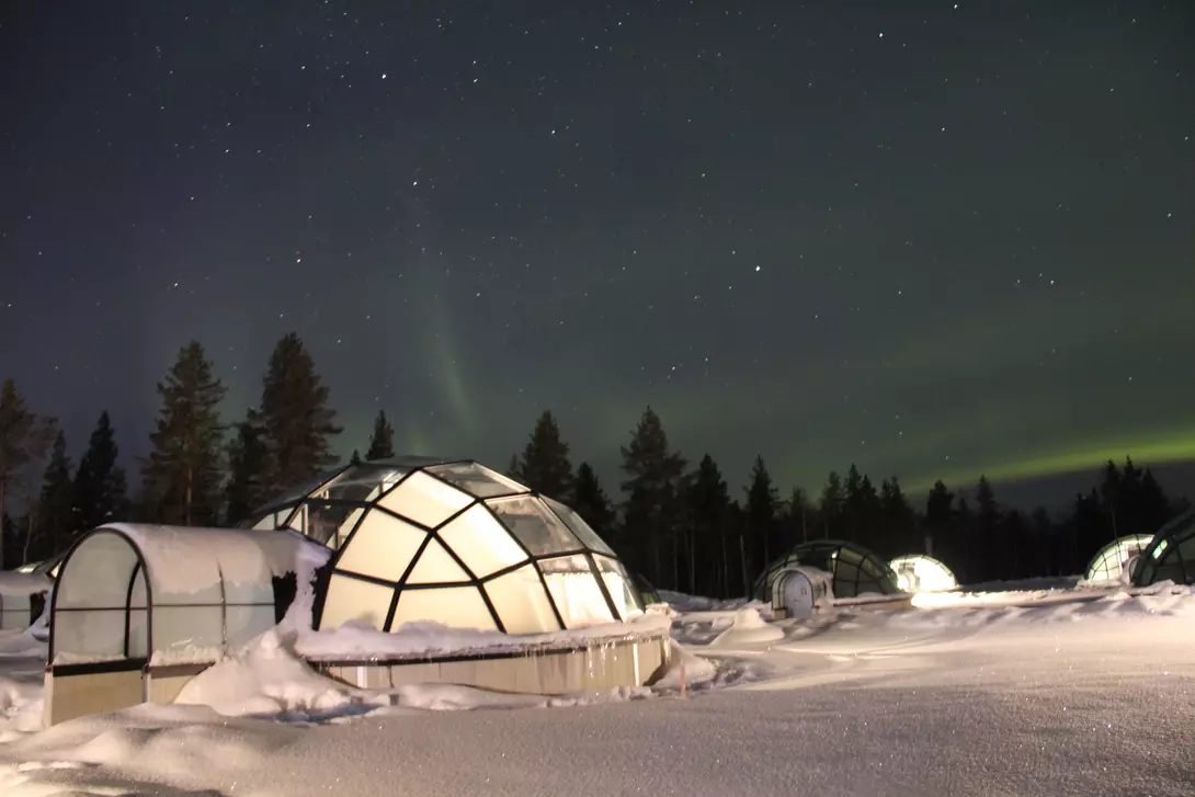Northern Lights (Aurora Borealis) dancing above Glass Igloos in Lapland.