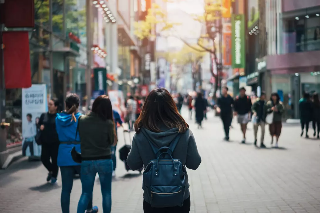 young asian woman walking down a crowded city street