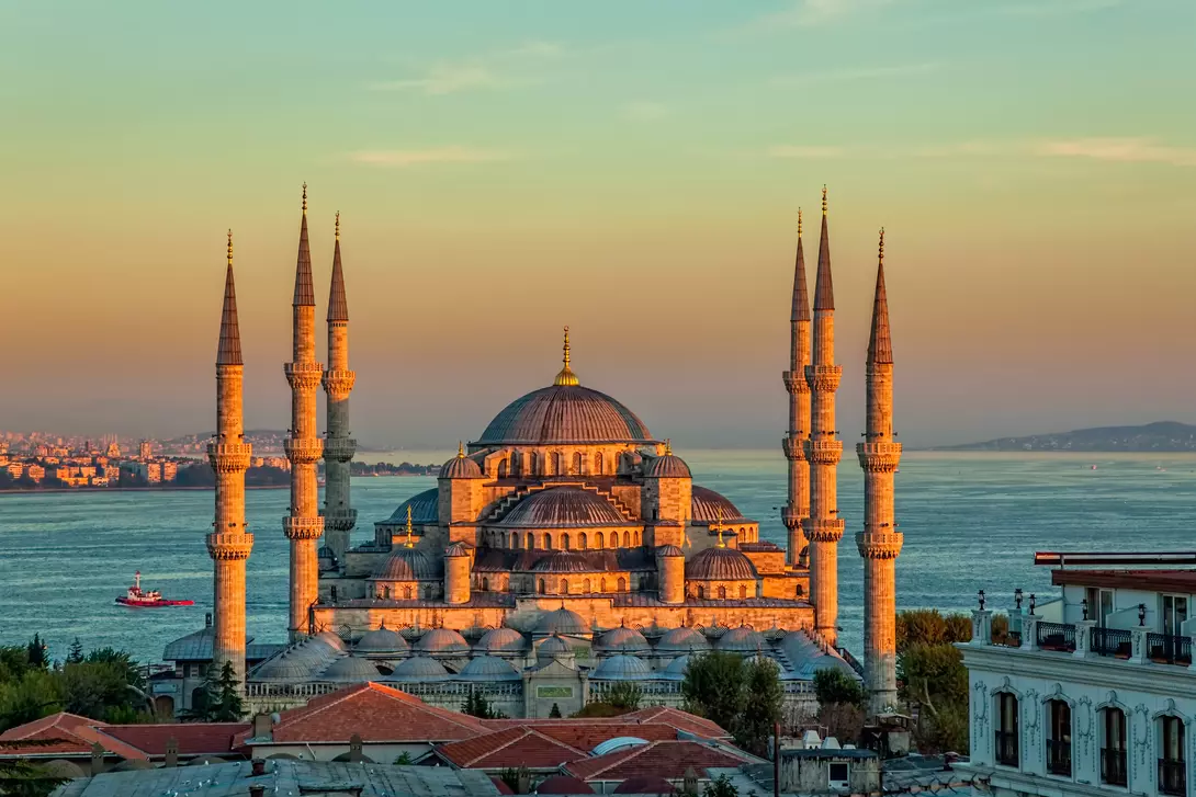 mosque with minarets on edge of water at sunset