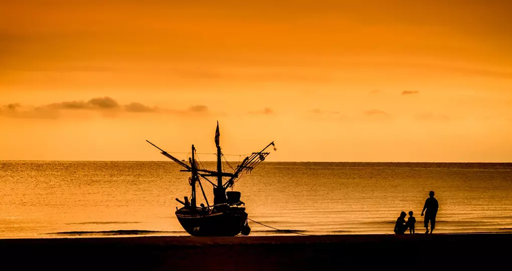 A fishing boat and family at sunset in Hua Hin A fishing boat and family at sunset in Hua Hin