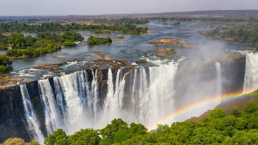 Aerial few of the world famous Victoria Falls with a large rainbow over the falls.