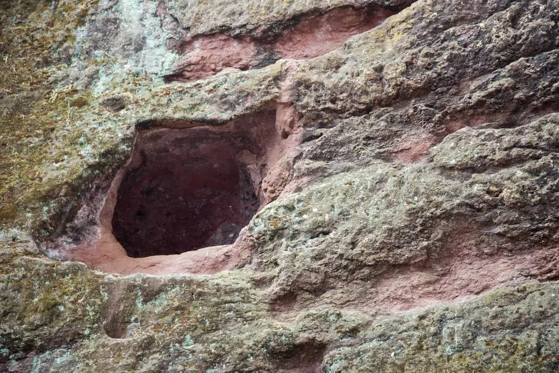 Holes in the rockface surrounding monolith rock-hewn church