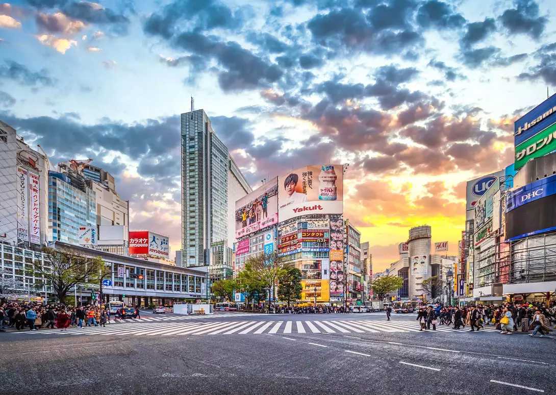 Pedestrians waiting at the traffic light to cross the street at Shibuya Crossing at sunset