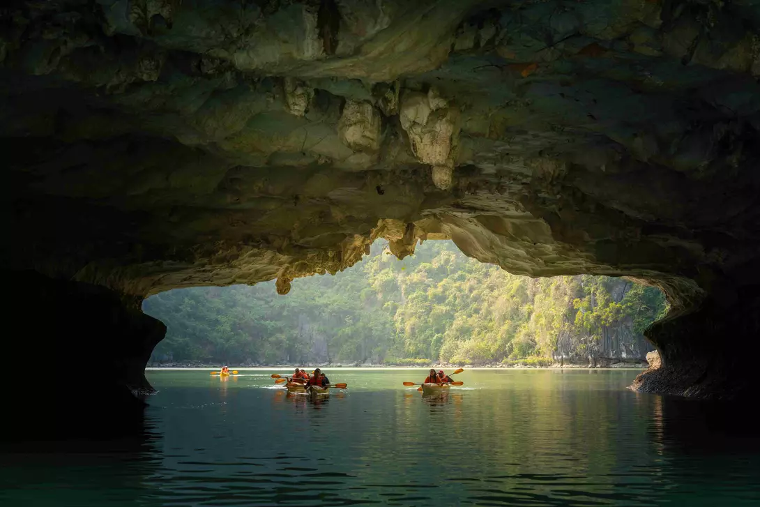 View of tourist exploring calm tropical bay with limestone mountains by kayak.