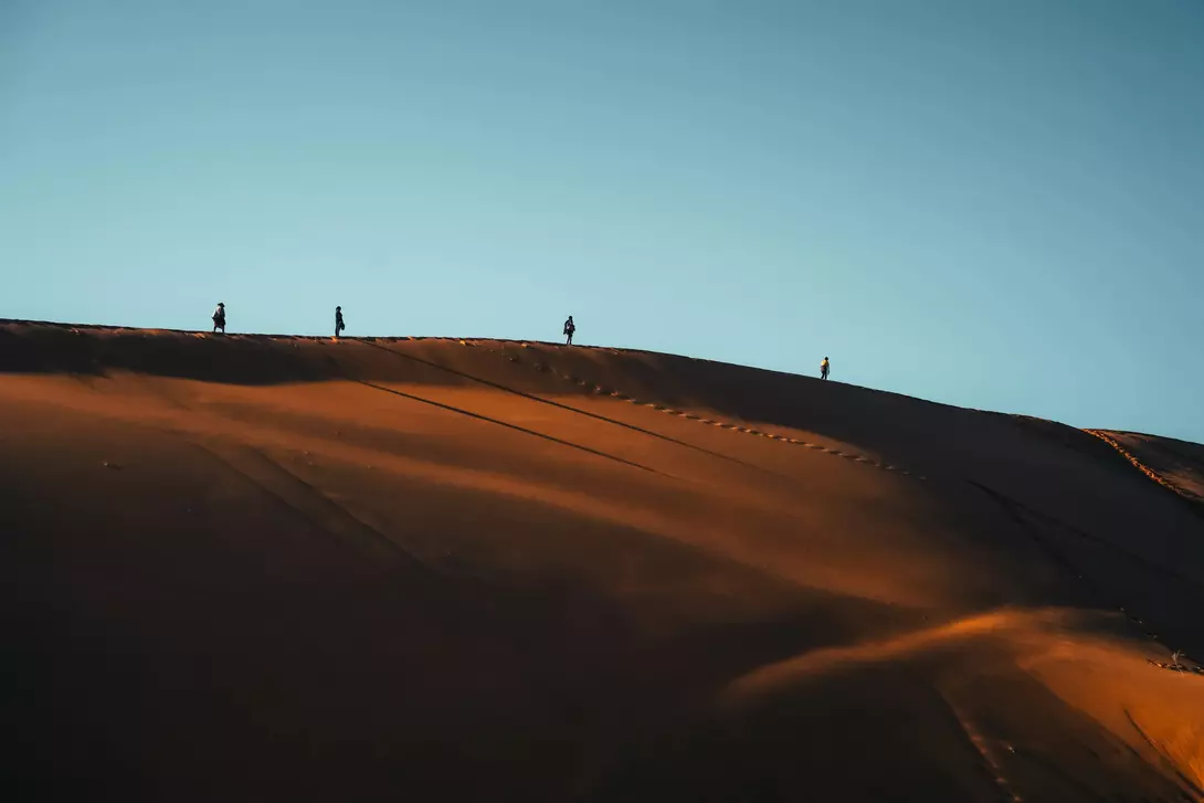 Silhouette tourist walking on Namibia Desert Dune