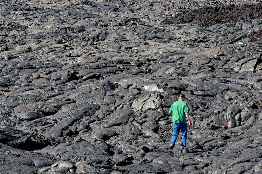 A hiker traverses the vast lava field from the Kilauea volcano at Volcanoes national park Hawaii